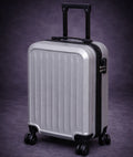 Silver suitcase with black handle and wheels on a dark purple background